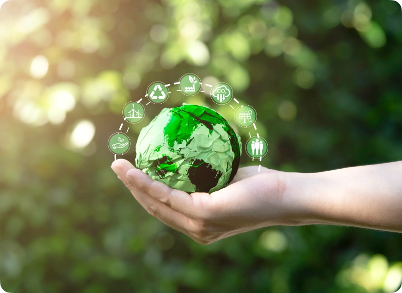 A hand holds a small earth globe with eco-friendly icons encircling it, symbolizing sustainable practices and the impact of environmental consulting.